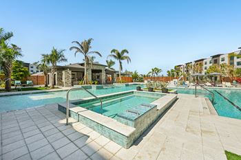 A swimming pool surrounded by palm trees and a building in the background.